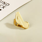 Single vintage gold eighth note metal clip resting on an aesthetic desk setup.