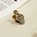 Single antique bronze treble clef metal clip securing vintage journal paper.