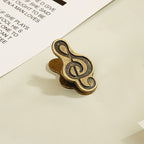Single antique bronze treble clef metal clip securing vintage journal paper.