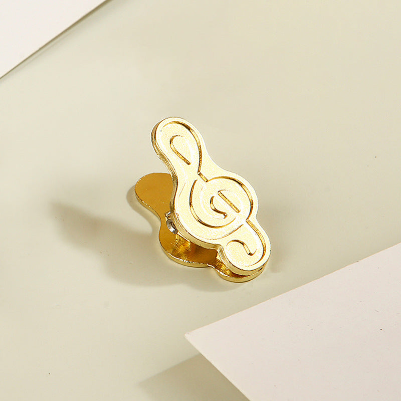 Single antique bronze treble clef metal clip securing vintage journal paper.