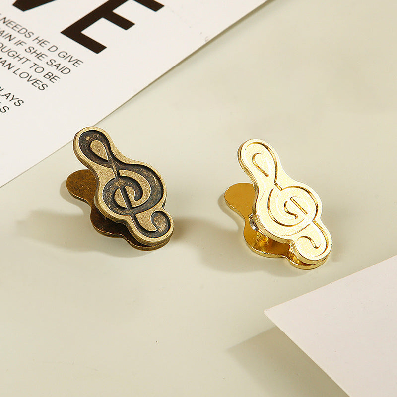 Mixed set of one bronze and one gold treble clef metal clips for creative journaling.