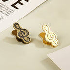 Mixed set of one bronze and one gold treble clef metal clips for creative journaling.