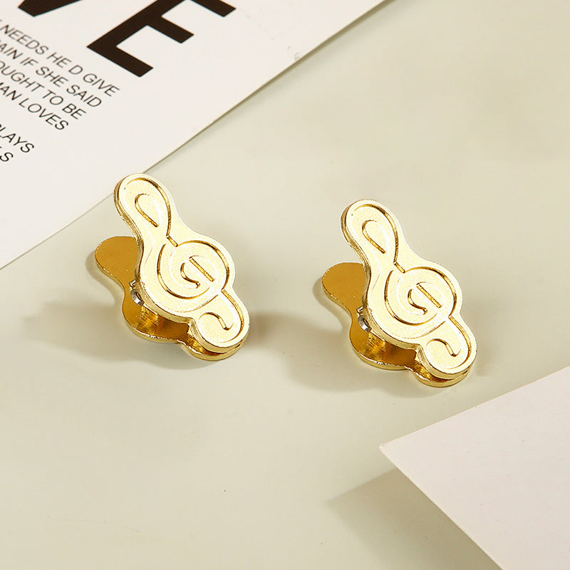 Pair of vintage gold treble clef planner clips displayed together.