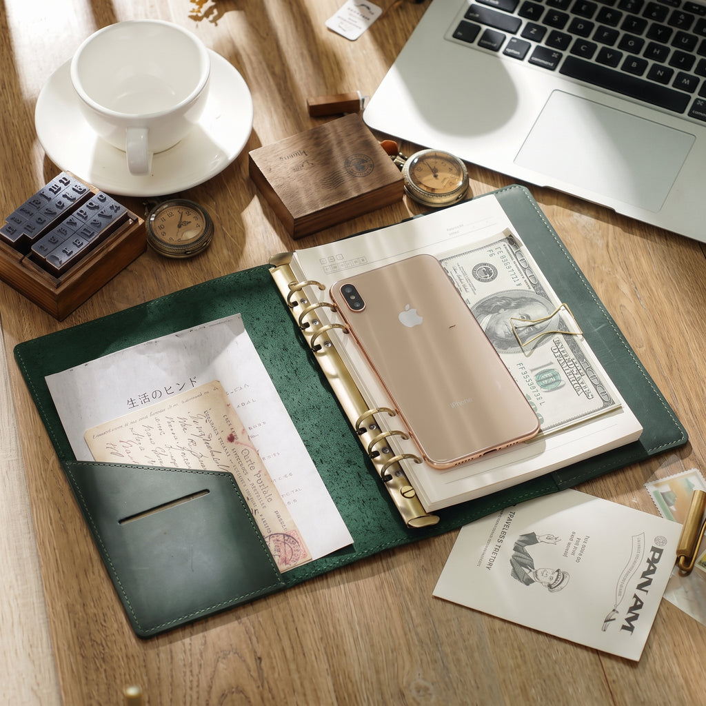 Open leather ring binder journal lying flat with pockets and refill pages