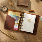Open leather ring binder journal showing refillable blank pages and rings