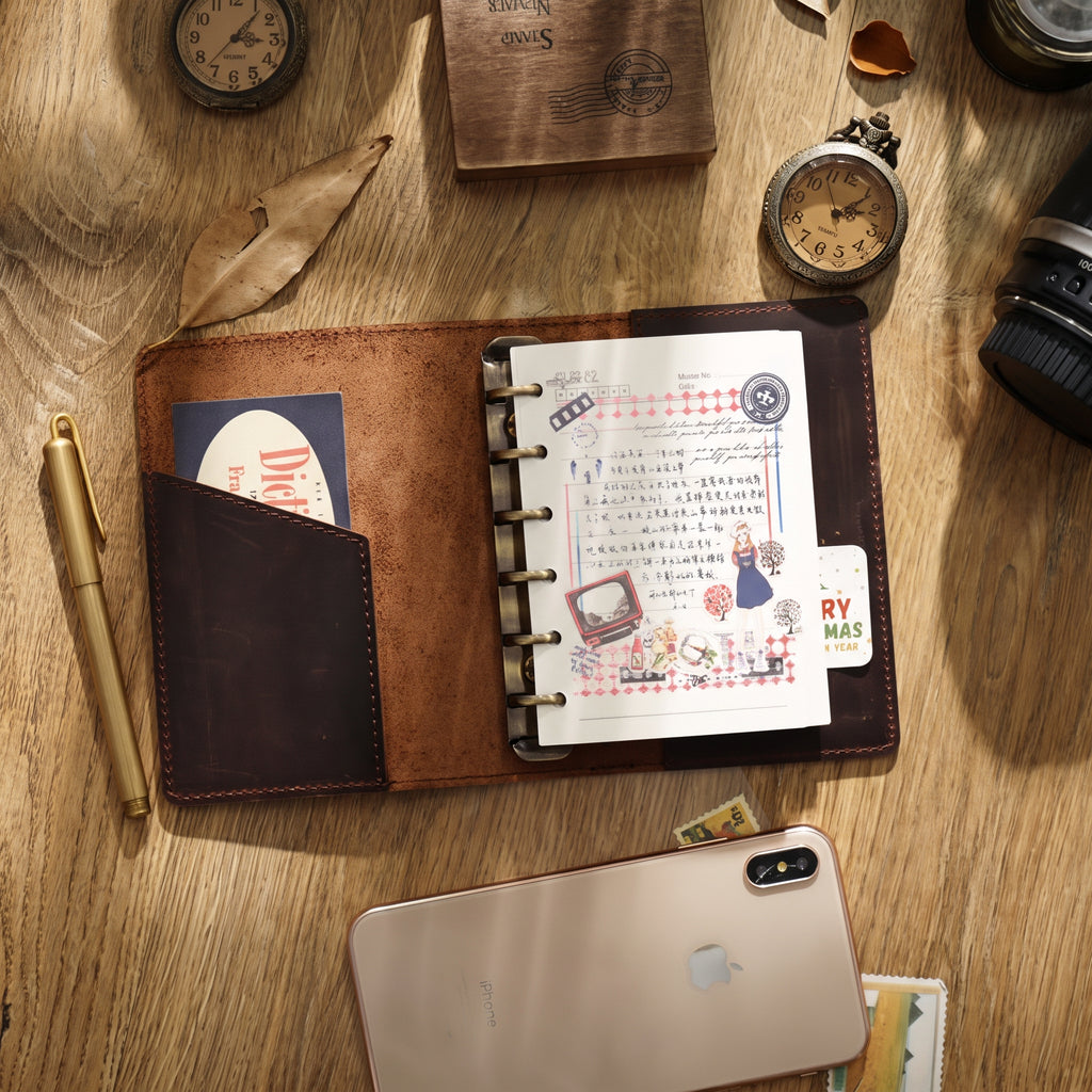 Open leather ring binder journal lying flat with pockets and refill pages