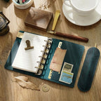 Blue leather ring binder journal with card pockets and pen on desk