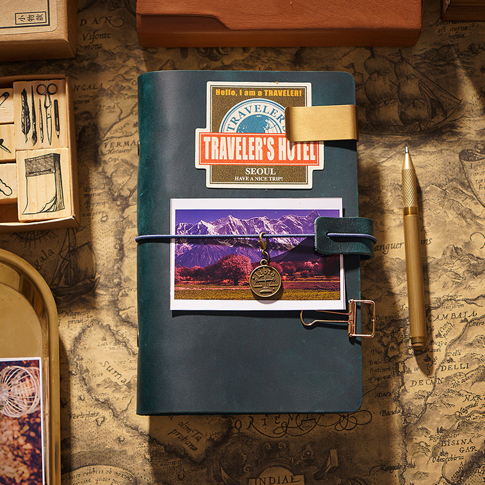 Dark green leather journal cover decorated with vintage stickers and travel ephemera
