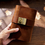 Hand holding small brown leather lock journal A7 showing pocket size