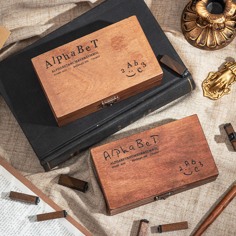 Wooden alphabet stamp box paired with a black ink pad on a vintage desk setup