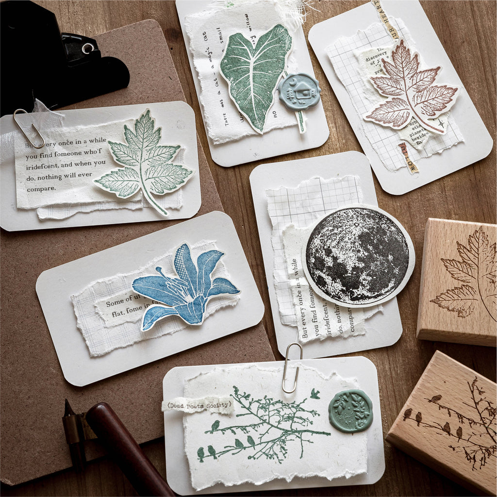 Assorted vintage wooden stamps and printed impressions scattered on dark surface, leaf motif, poetic text, circular texture, and botanical patterns for scrapbooking