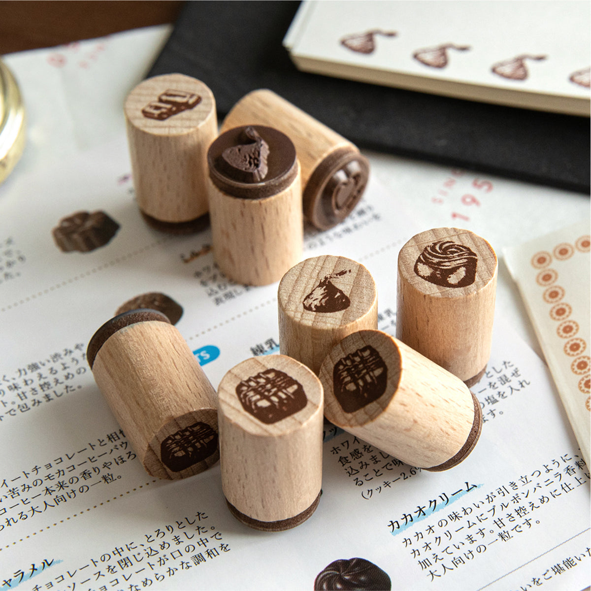 Beech wood dessert stamps scattered on paper with coffee beans and journal pages