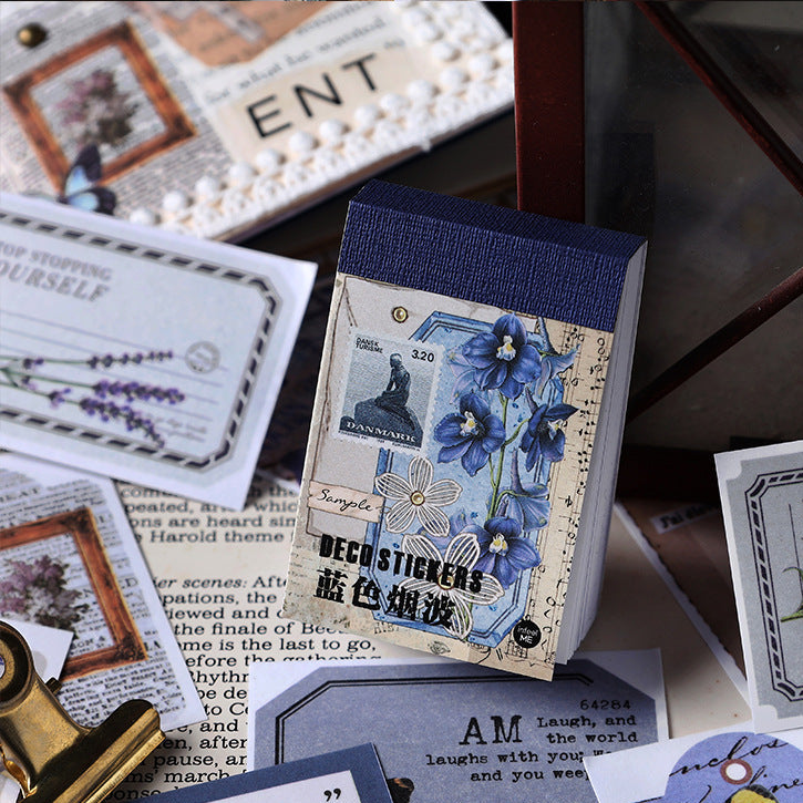 Blue Mist vintage washi sticker book with blue floral and water-themed illustrations scattered on aged paper beside antique journaling supplies