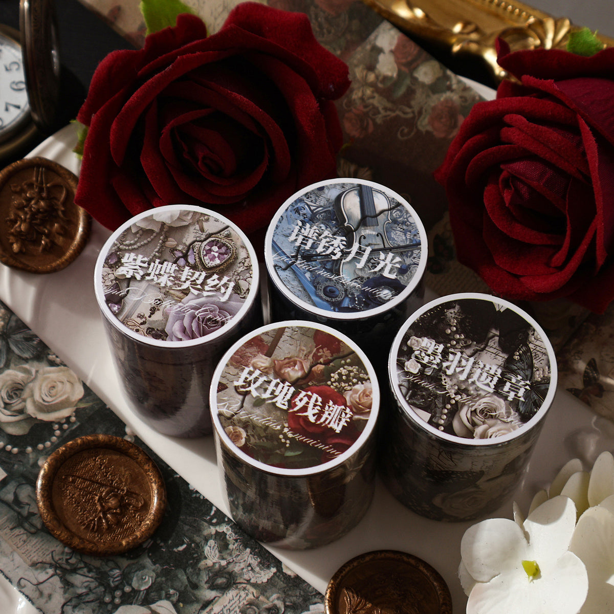 Four vintage butterfly washi tape rolls among red roses and wax seals