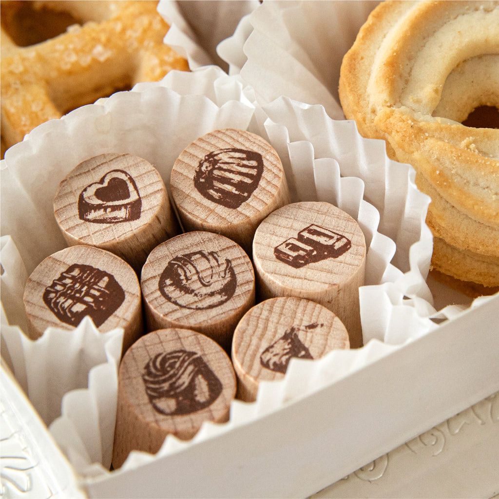 Chocolate stamps arranged in paper candy cups beside croissants
