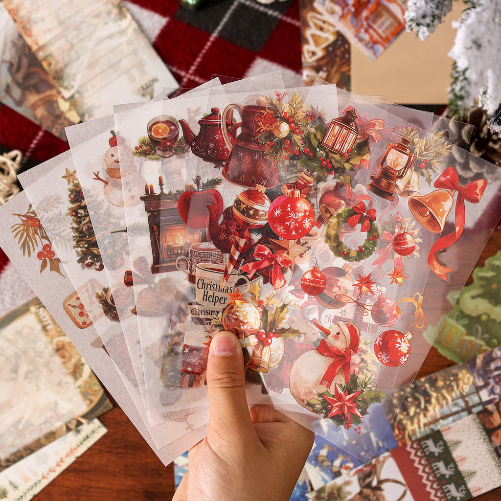 Hand holding layered vintage Christmas ephemera pile with red floral stickers and aged paper pieces