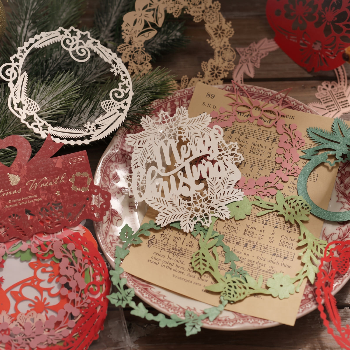 Laser cut Christmas wreaths and snowflakes layered over vintage music sheet paper