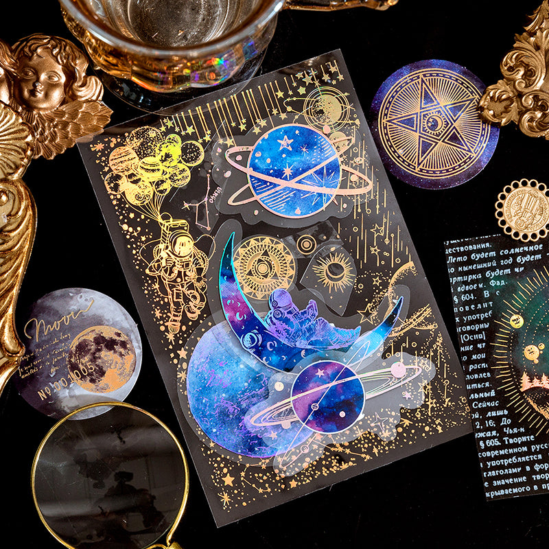 Close up of holographic gold foil stickers featuring astronauts planets and stars on transparent PET