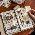 Vintage coffee notepad strips spread across open journal with planner clips, showing baked by artisans, process notes, and dark roast typography for scrapbook layering