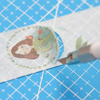 Hand cutting paper tape with a precision craft knife on cutting mat