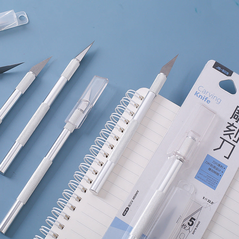 Craft knife set with spare blades and safety storage case on notebook