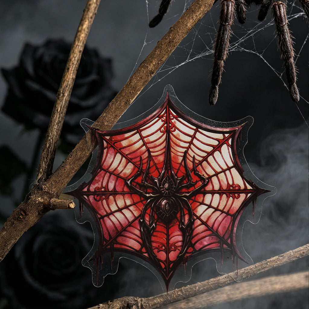 Crimson spider web sticker displayed on bare branches in the dark`