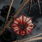 Crimson spider web sticker displayed on bare branches in the dark`