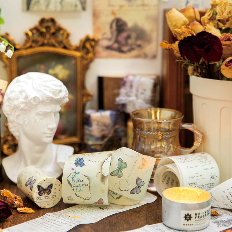 Dark academia desk setup with vintage washi tape rolls dried roses pearl beads and classical bust sculpture

