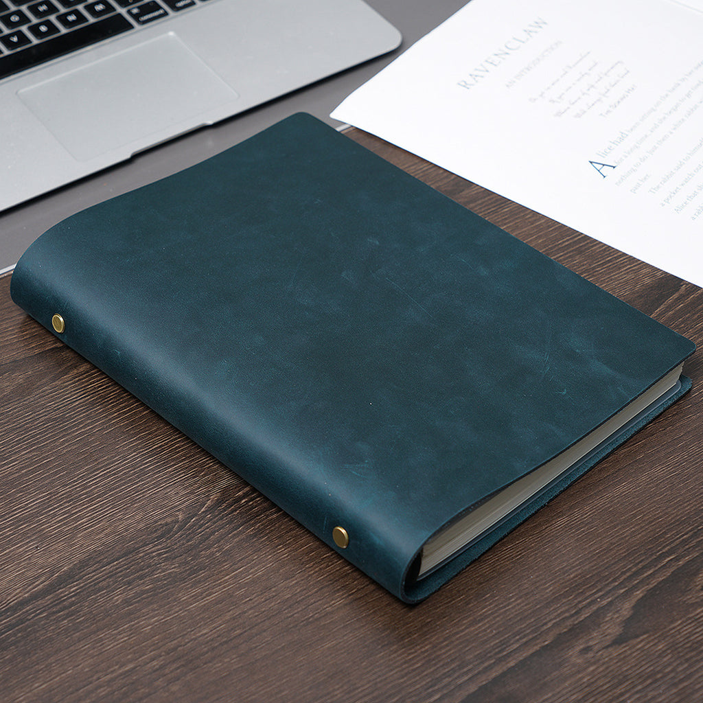 Dark green B5 leather ring binder journal on desk beside laptop