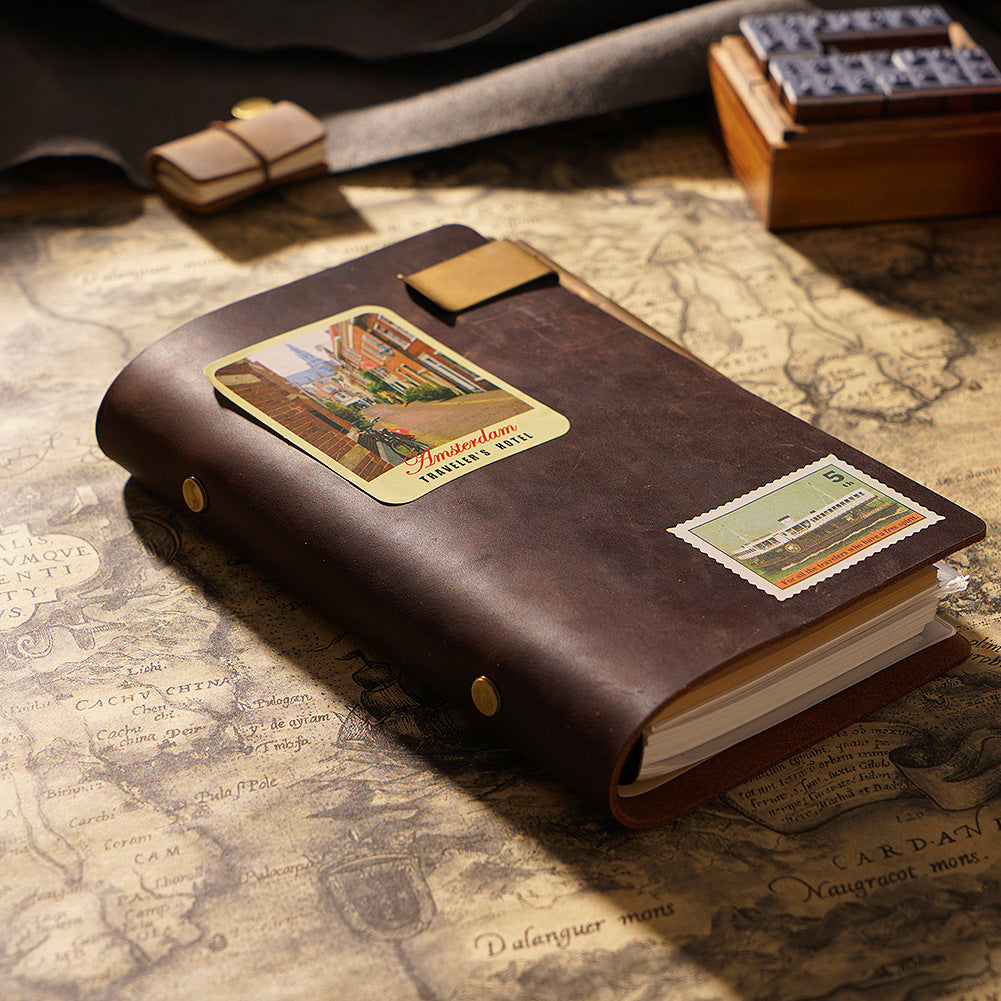Coffee-colored crazy horse leather notebook decorated with Amsterdam hotel and vintage postage stickers on a retro map background.