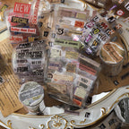Scattered vintage die-cut tape fragments with bold headlines ticket stubs and handwritten snippets on clear PET backing
