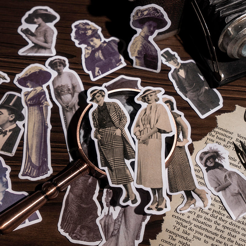  Close-up of scattered vintage character stickers with white die-cut edges under a brass magnifying glass, showing women in period hats and long dresses.