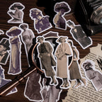  Close-up of scattered vintage character stickers with white die-cut edges under a brass magnifying glass, showing women in period hats and long dresses.