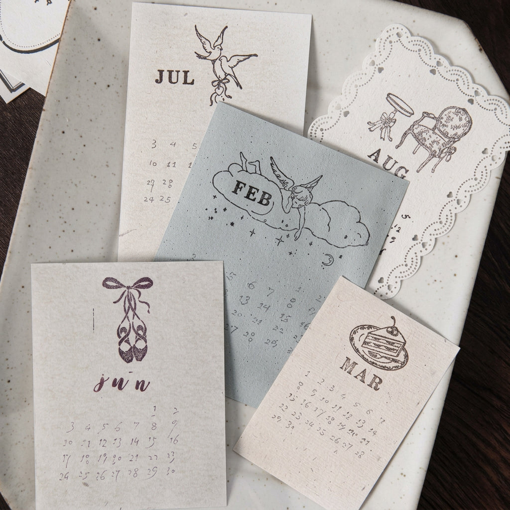 Flat lay of stamped botanical and figure motifs on kraft and cream cards