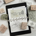 Fairy-tale motifs stamped into a black journal beside beech wood stamps