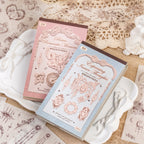 Dream Voyage sticker books in pink and blue on vintage lace with angel figurine