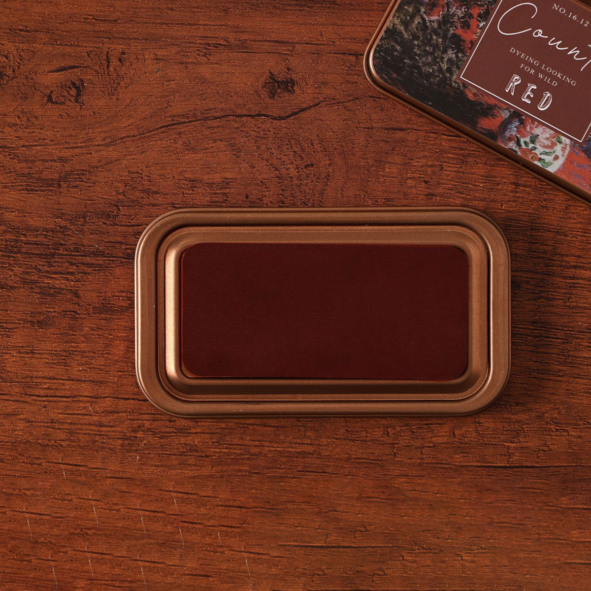 Vintage iron box ink pad in Earl Red open on wood, red lid beside