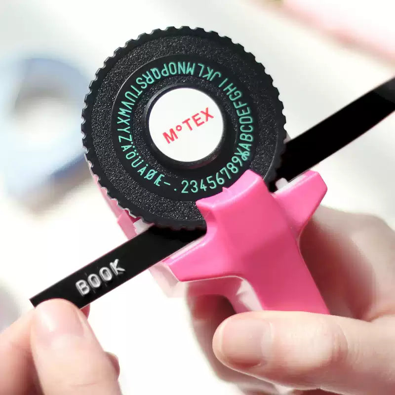 Pink embossing label maker pressing raised letters onto black tape