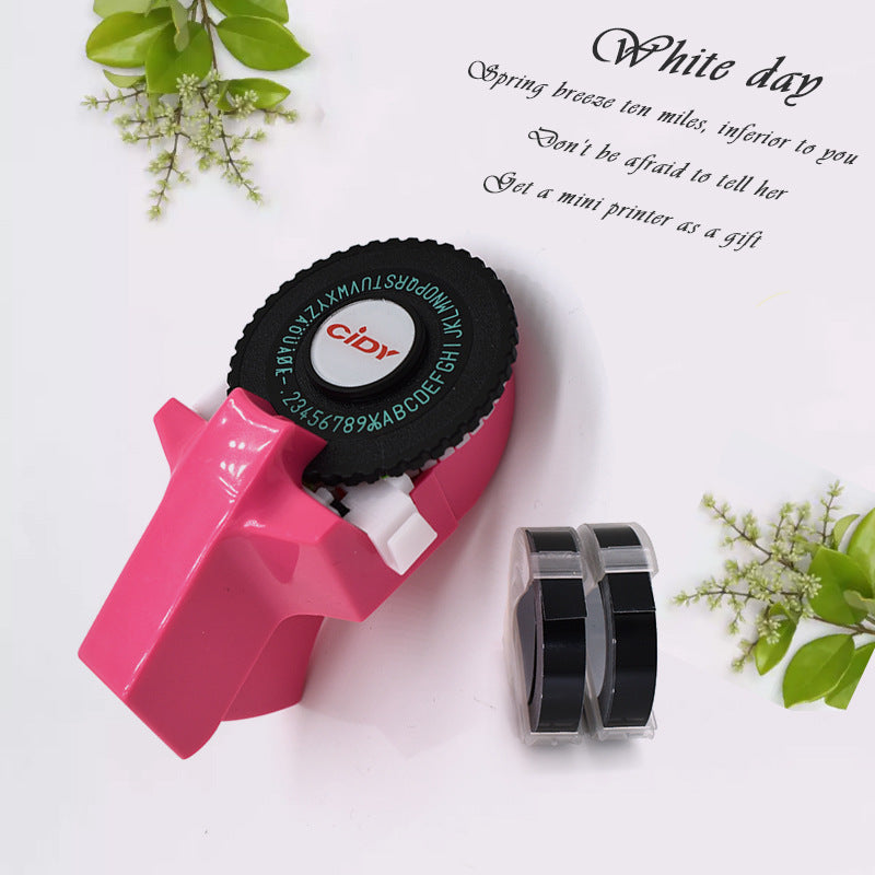 Pink embossing label maker with tape roll on desk flat lay
