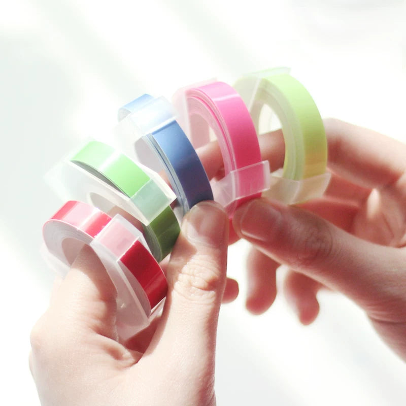 Hands holding a fan of colorful embossing label tape rolls
