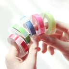 Hands holding a fan of colorful embossing label tape rolls