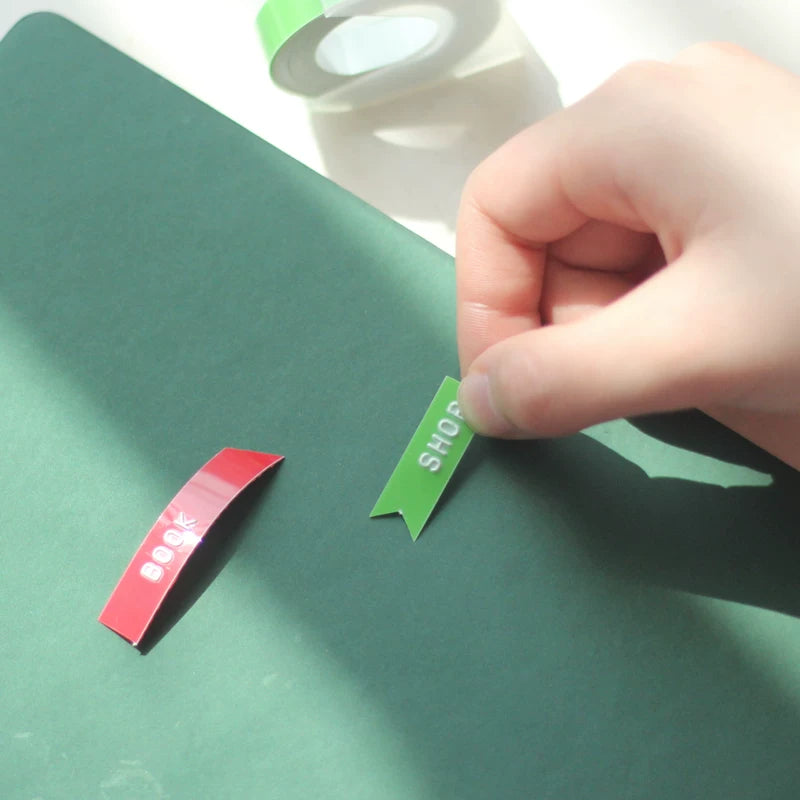 Peeling green embossing tape from its roll to label a surface