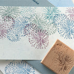 Colorful stamped impression of firework and starburst pattern on textured paper, vintage wooden rubber stamp shown in corner for journal decoration