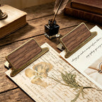 Multiple walnut wood clips styled with botanical prints and letters on desk