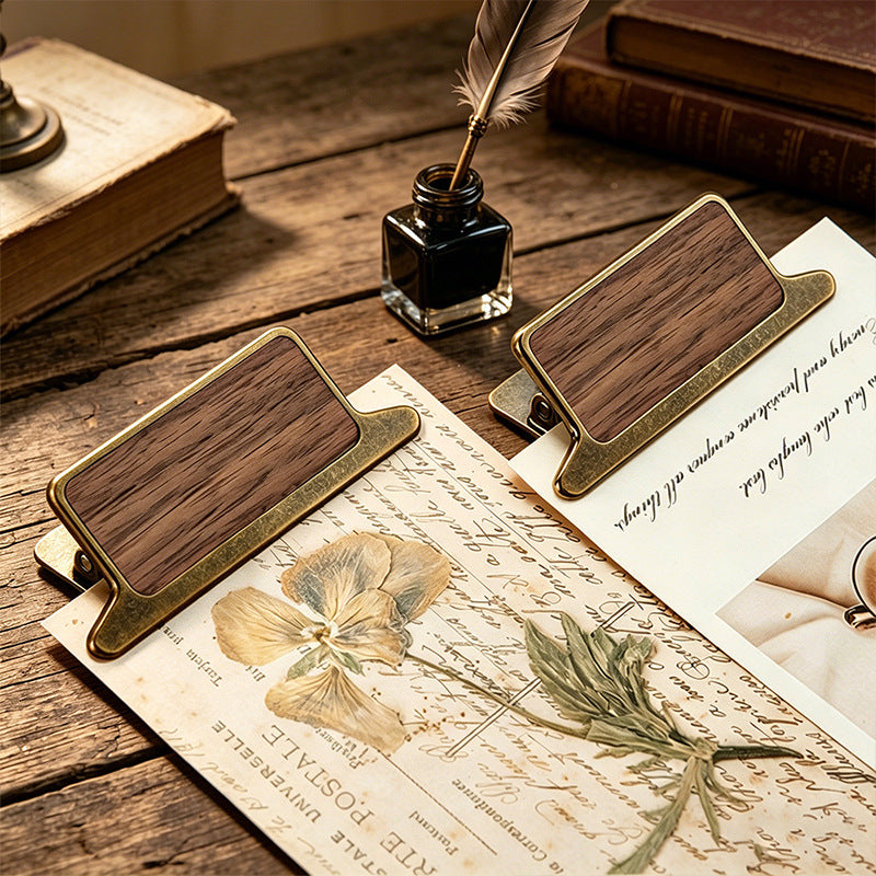 Multiple walnut wood clips styled with botanical prints and letters on desk