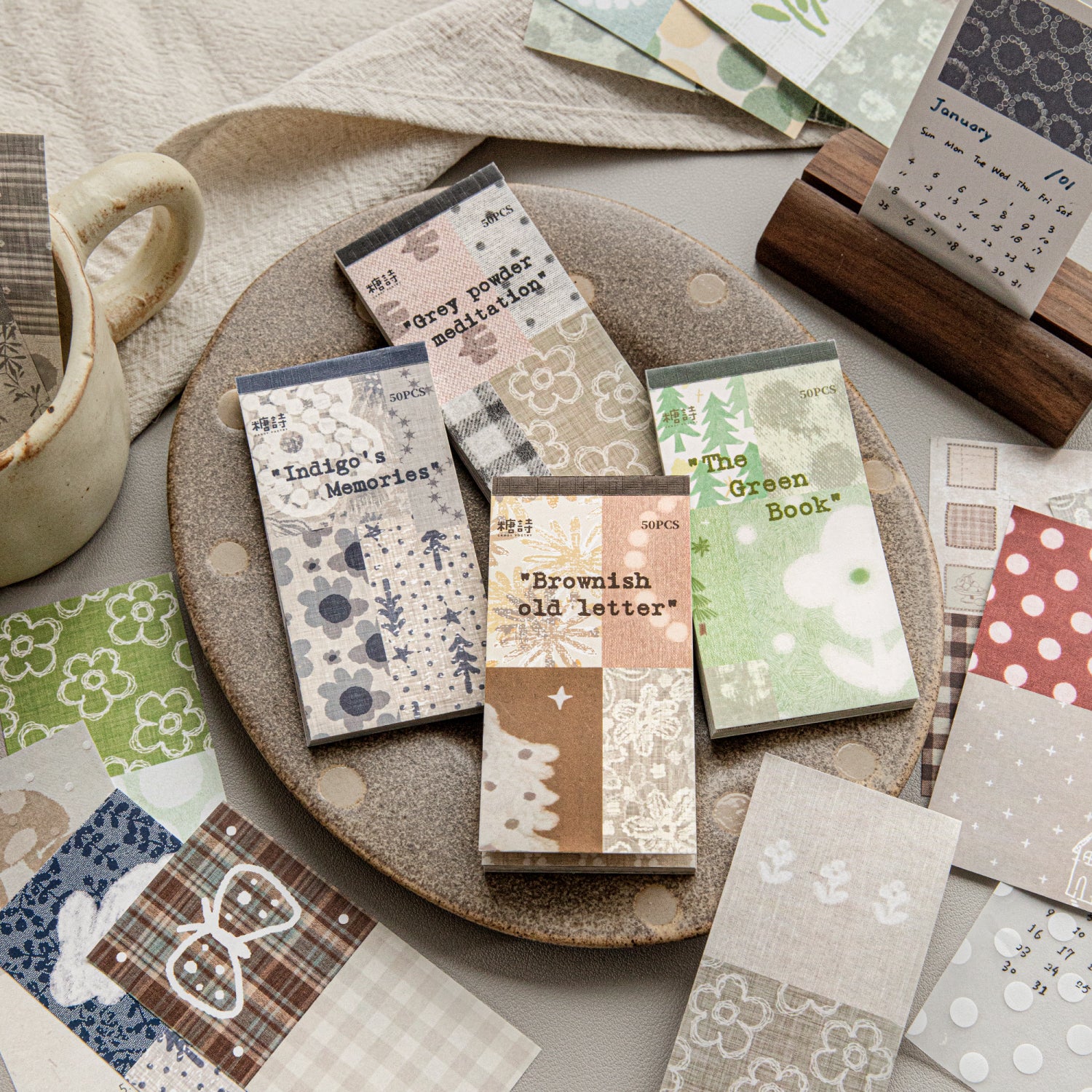 Four vintage mixed ephemera paper packs in indigo green brown and pink tones, lightweight paper and PET overlays with botanical and calendar prints, pre-cut scrapbook collage supplies
