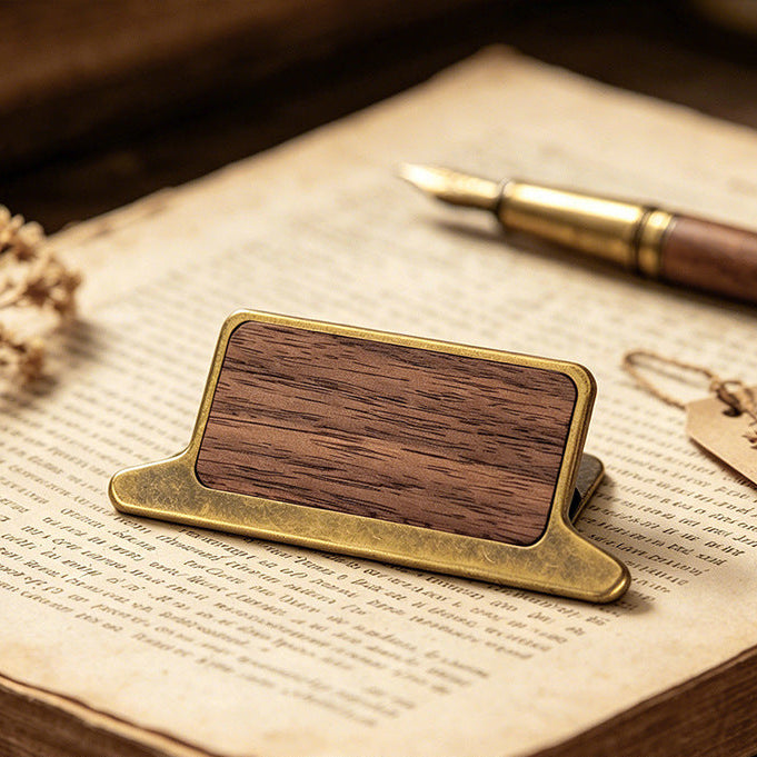 Walnut wood journal clip with antique bronze frame resting on open book pages
