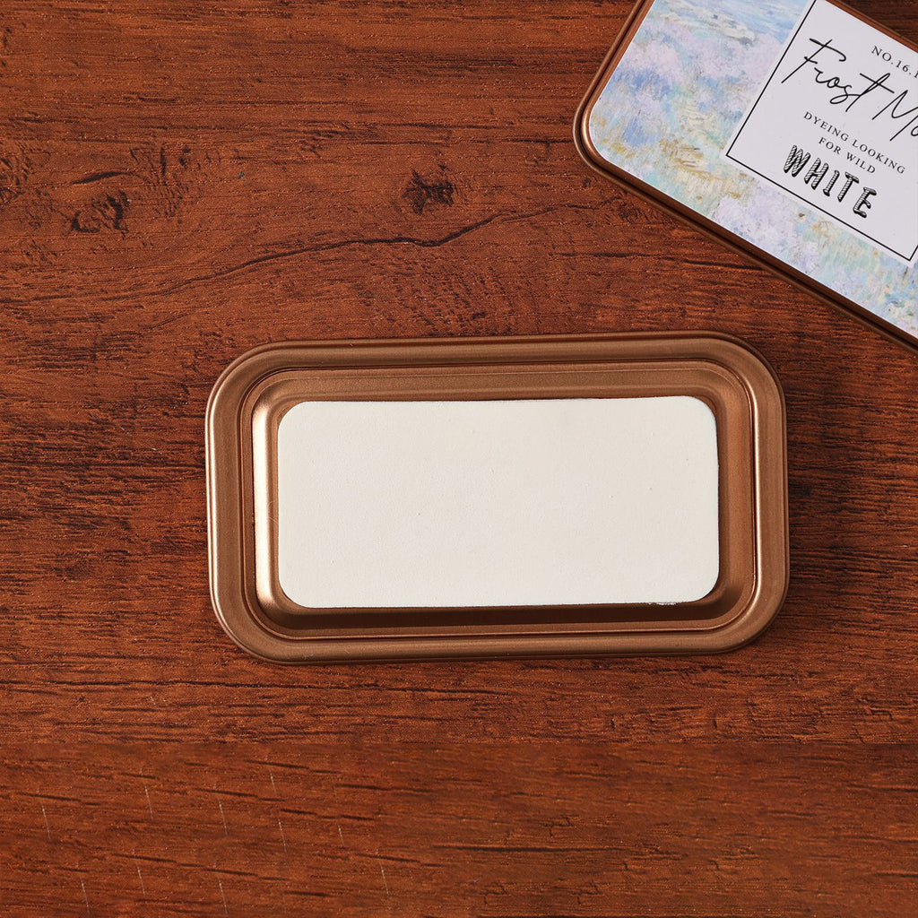 Vintage iron box ink pad in Frost White open on wood, white moon lid beside