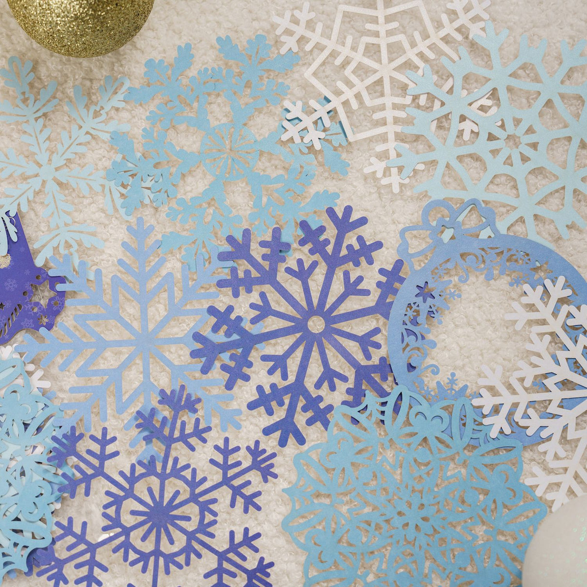 Blue and white laser cut snowflake lace paper on light blue background