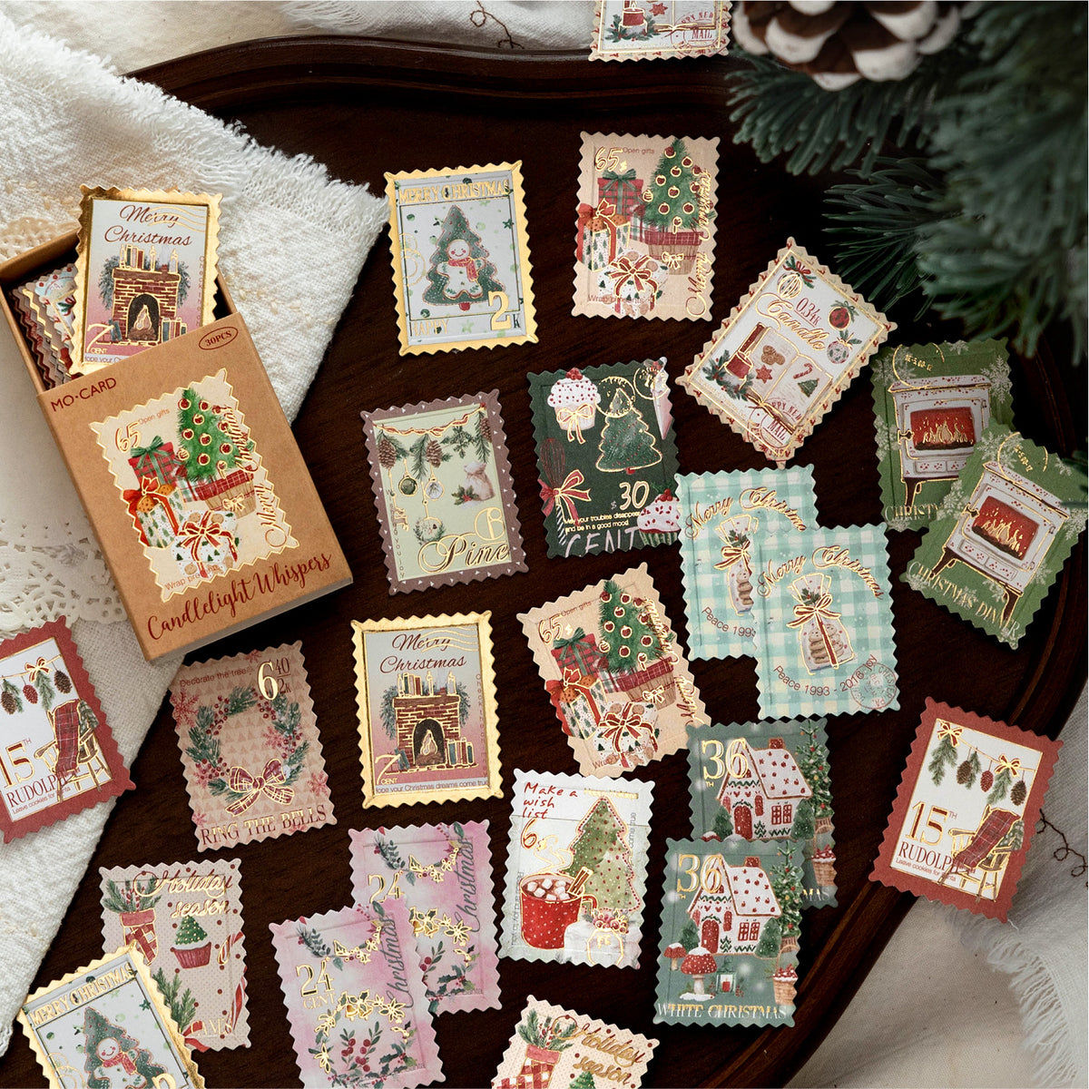 Golden Bells and Elk Christmas stickers spread across a vintage desk with lace and greenery